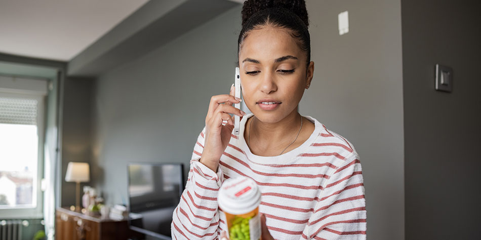 Woman holding a pill bottle and talking on the phone.